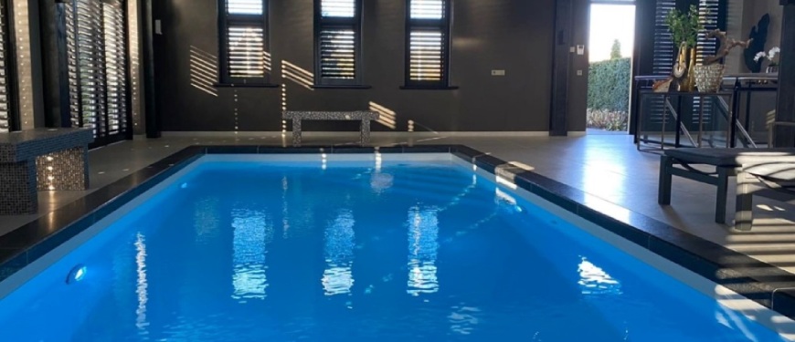 Liever een binnenzwembad aanleggen? Bij Aqua Optimaal kan het allemaal Binnen zwembad met donkere muren en jaloezieën.