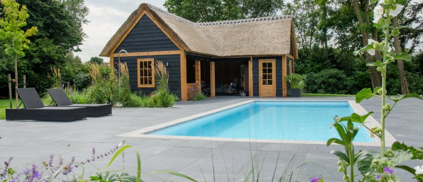 Zwembad in een landelijke tuin met een rieten dak poolhouse.